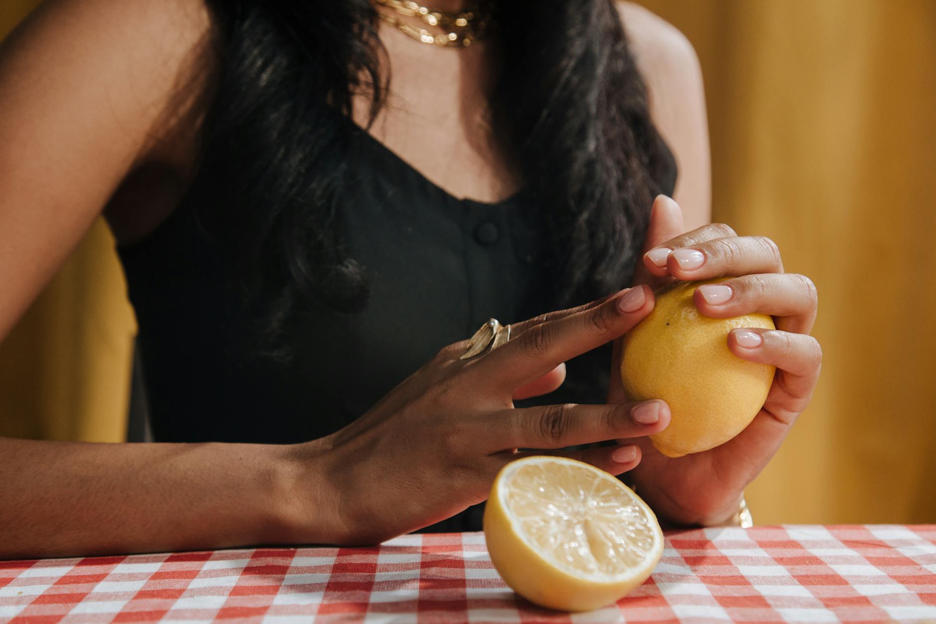 Close-up of hands holding an orange vibrator against a minimalistic purple backdrop, showcasing modern sensuality.