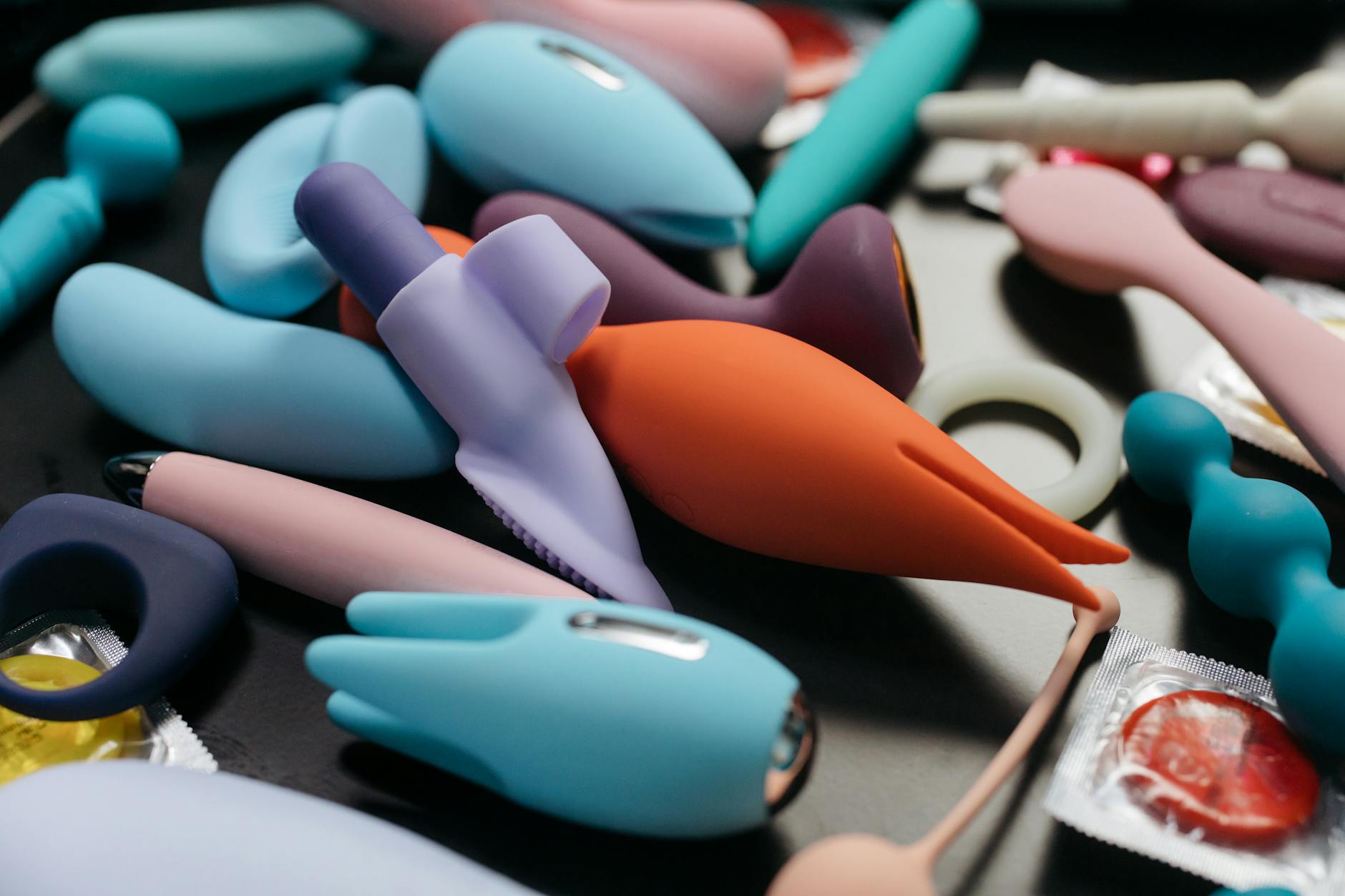 A hand holding a sleek blue clitoral vibrator against a purple background