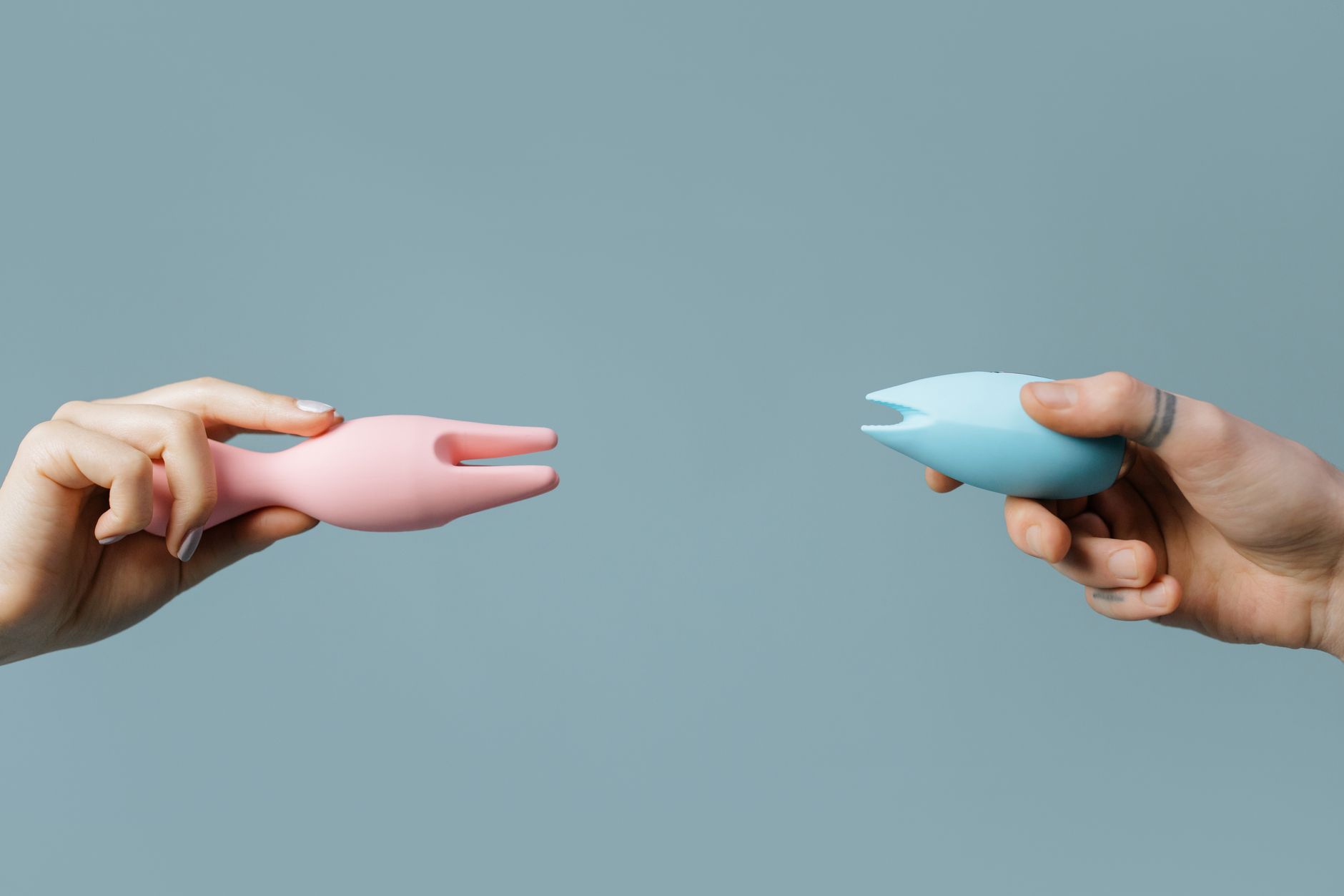 Close-up of hands holding colorful personal massagers against a soft background